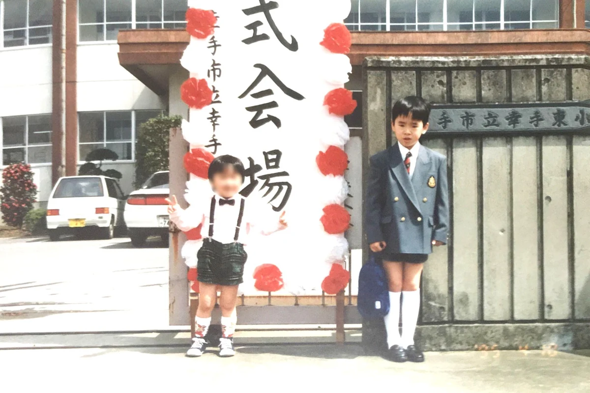 幸手で育った頃の写真。入学式の看板の前に立つ子どもたち